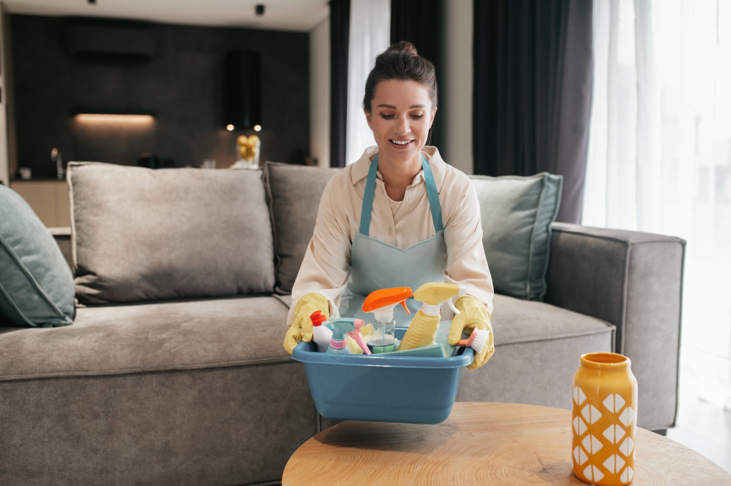 Dark-haired woman carrying a basin with difinfection appliances Complete Upholstery Cleaning Guide for a Fresher Home